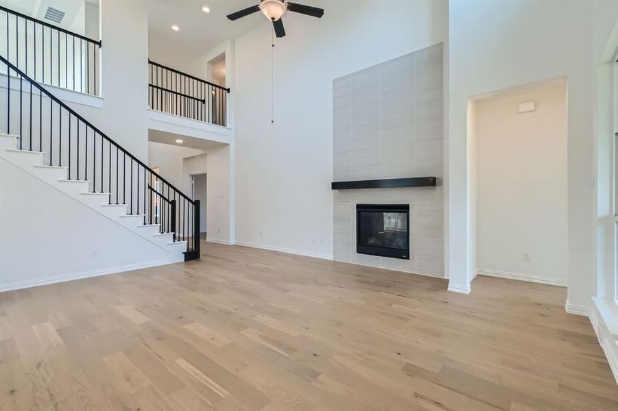 Unfurnished living room with a high ceiling, light wood-type flooring, and a fireplace