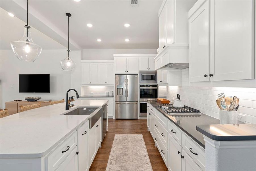 Kitchen featuring stainless steel appliances, hanging light fixtures, dark hardwood / wood-style flooring, decorative backsplash, and a large island