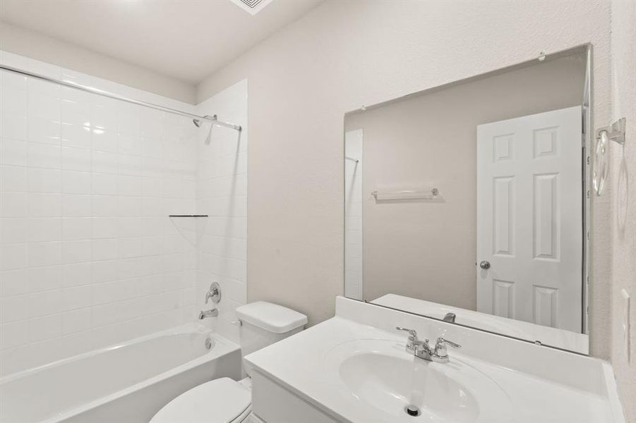 The secondary bath features tile flooring, white cabinetry and light countertops and a shower/tub combo. Perfect for accommodating any visiting family and friends.