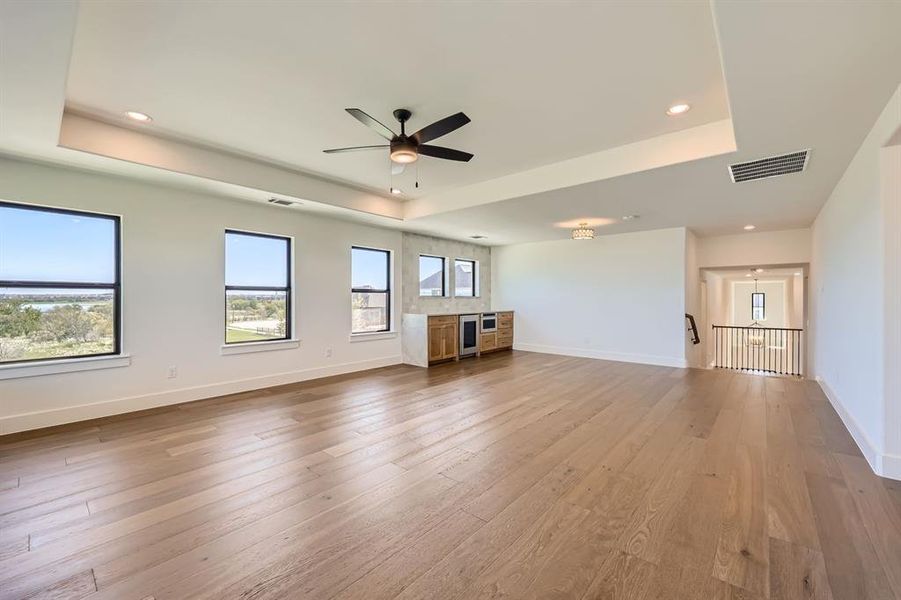 Unfurnished living room with a tray ceiling, hardwood / wood-style floors, and ceiling fan