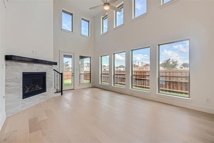 Living room featuring a corner fireplace, ceiling fan, and a wealth of natural light