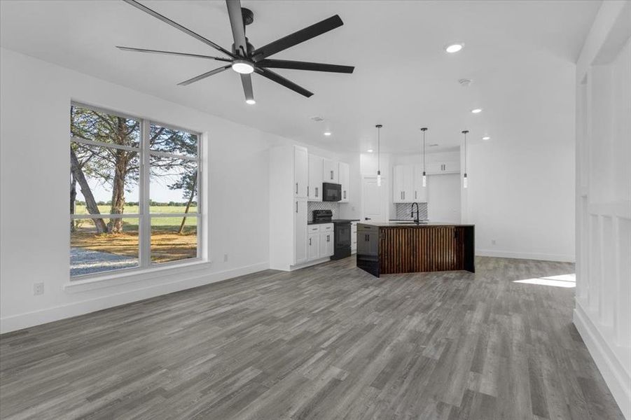 Unfurnished living room with ceiling fan, sink, and light hardwood / wood-style flooring