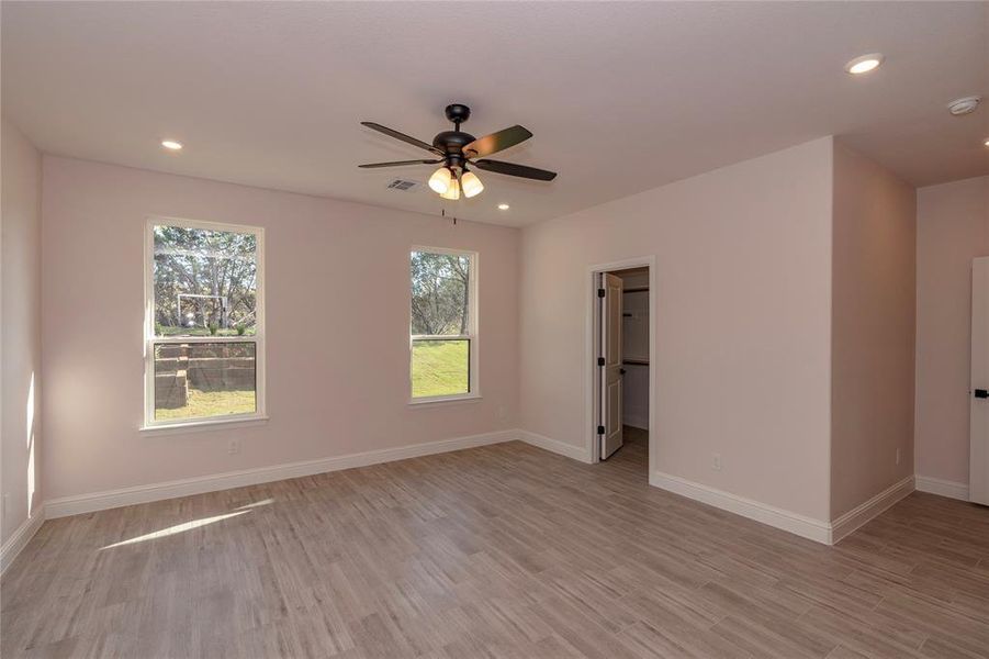 Unfurnished room with a wealth of natural light, ceiling fan, and light hardwood / wood-style flooring