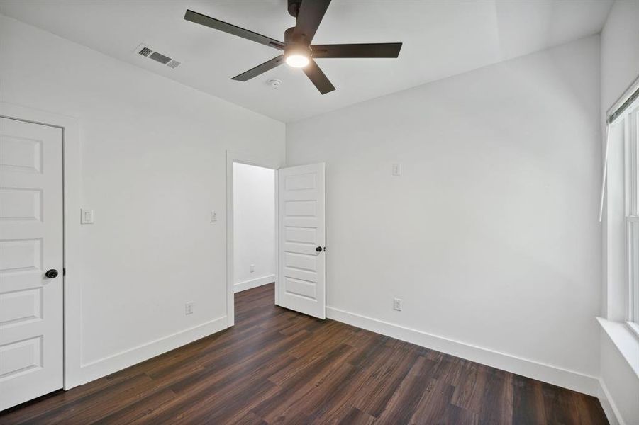 Empty room with dark wood-type flooring and ceiling fan