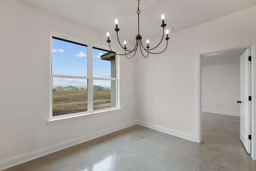 Spare room featuring a wealth of natural light, concrete flooring, and an inviting chandelier