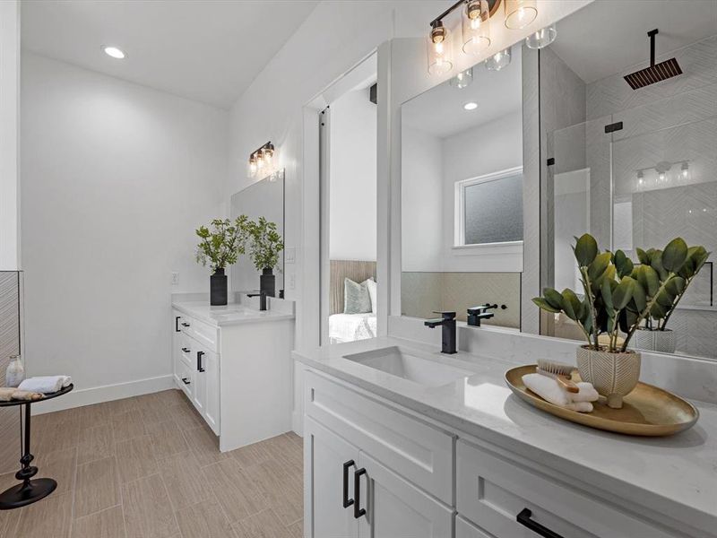 Separate counter and sink spaces offer ample room on both the countertops and in the cabinets, complemented by tasteful lighting and hardware.