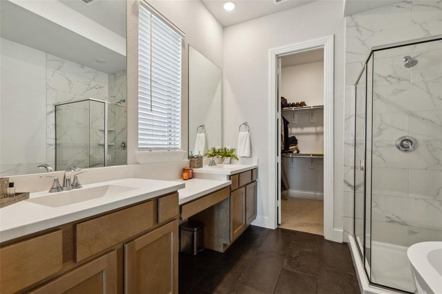 Primary bathroom featuring double vanities, knee space for a beauty bench, open to walk in closet.