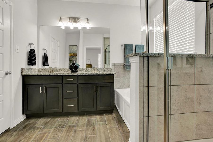 Bathroom with independent shower and bath, hardwood / wood-style flooring, dual bowl vanity, and tile walls