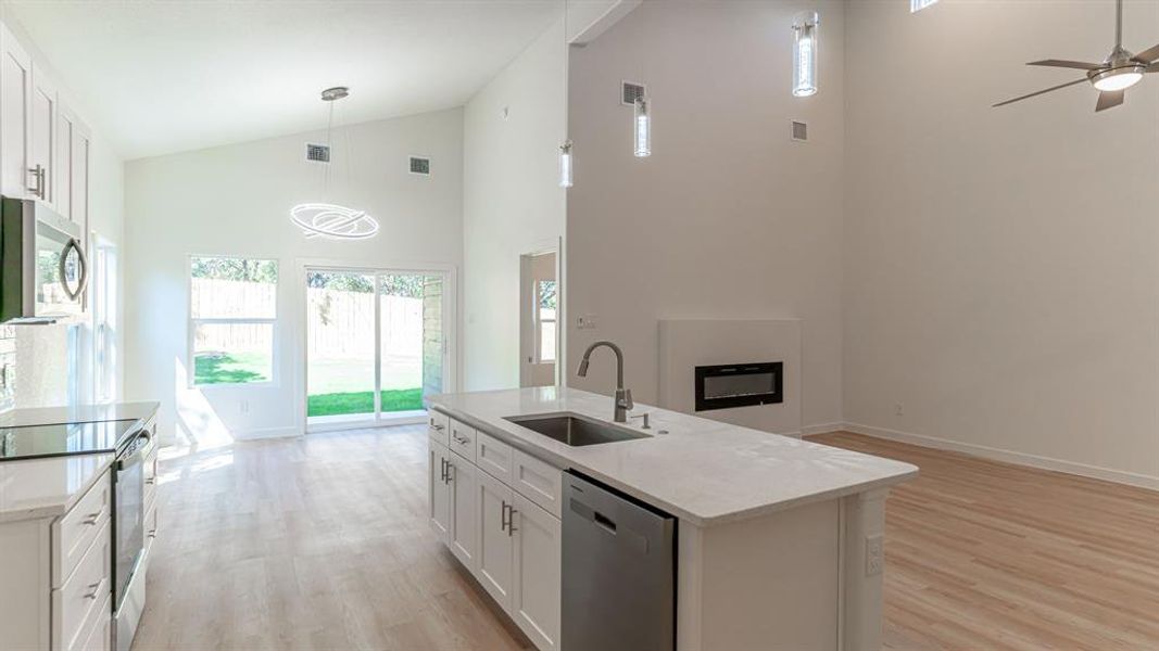 Kitchen with sink in island and contemporary decorative lighting