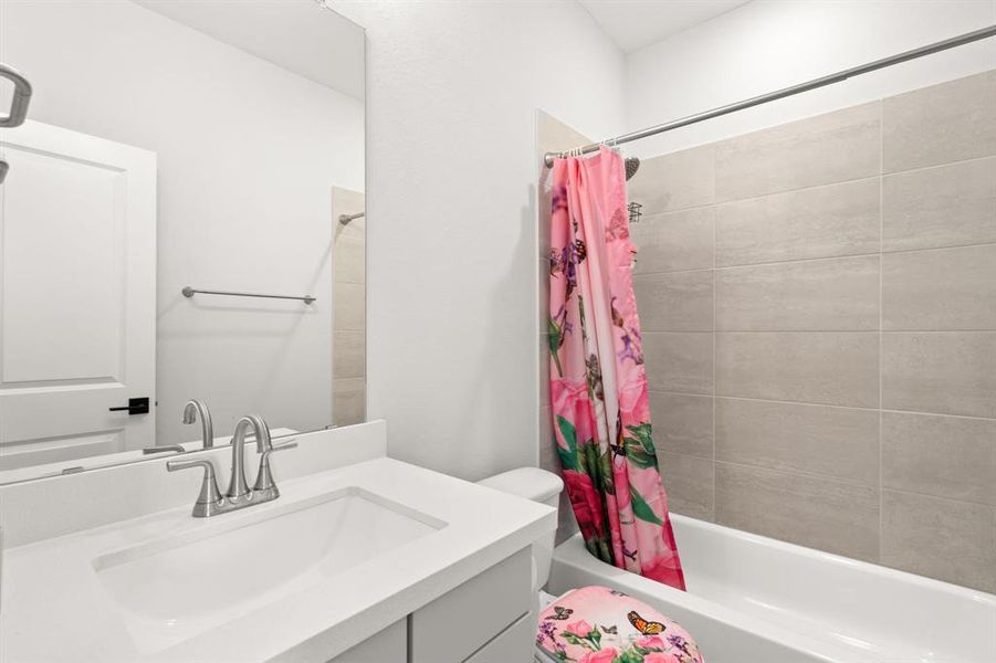The fourth bedroom's bathroom includes a tiled shower/tub combination, a stylish grey vanity, and a toilet, offering a modern and functional space for daily use.