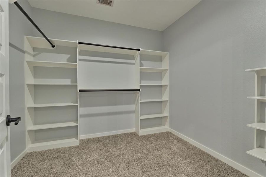 Second floor primary walk in closet with built in shelves and hanging space.