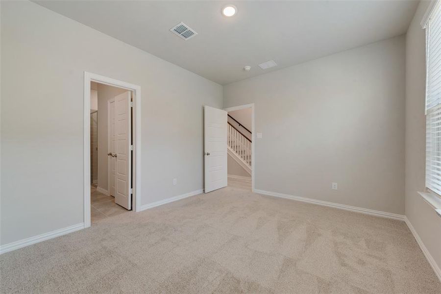 Unfurnished bedroom with ensuite bath and light colored carpet