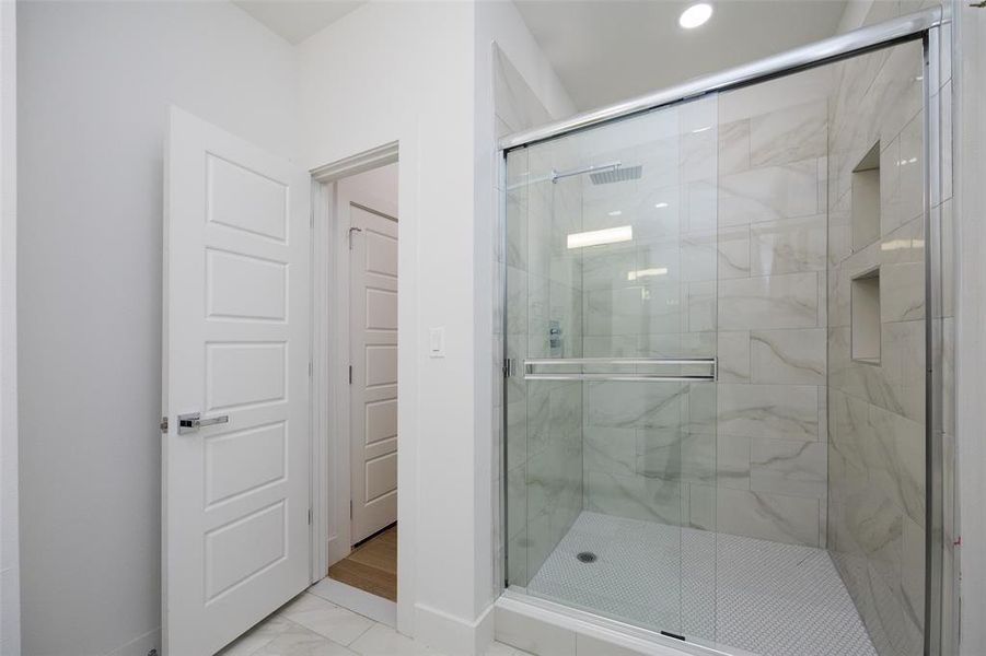 Bathroom featuring a shower with door and tile flooring