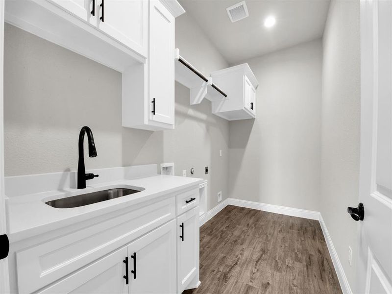 Laundry room featuring cabinets, washer hookup, hookup for an electric dryer, hardwood / wood-style floors, and sink