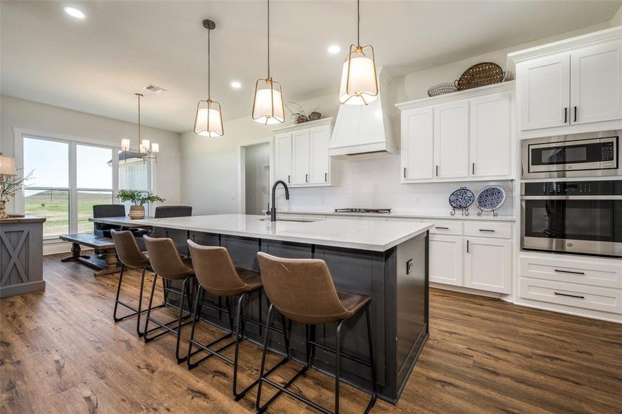 Kitchen with white cabinets, stainless steel appliances, a center island with sink, dark wood-type flooring, and sink