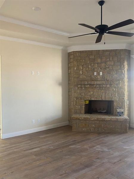 Unfurnished living room with ceiling fan, a fireplace, crown molding, and hardwood / wood-style floors