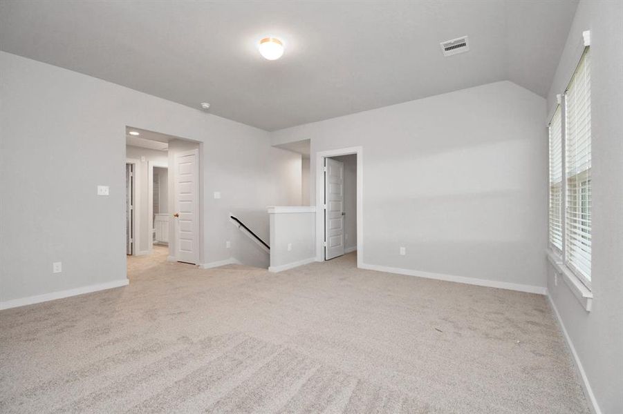 Come upstairs and relish a day of relaxation in this loft / game room area! Ideal as an additional living space or game room, it boasts plush carpeting, high ceilings, custom paint, and windows that flood the area with abundant natural light.