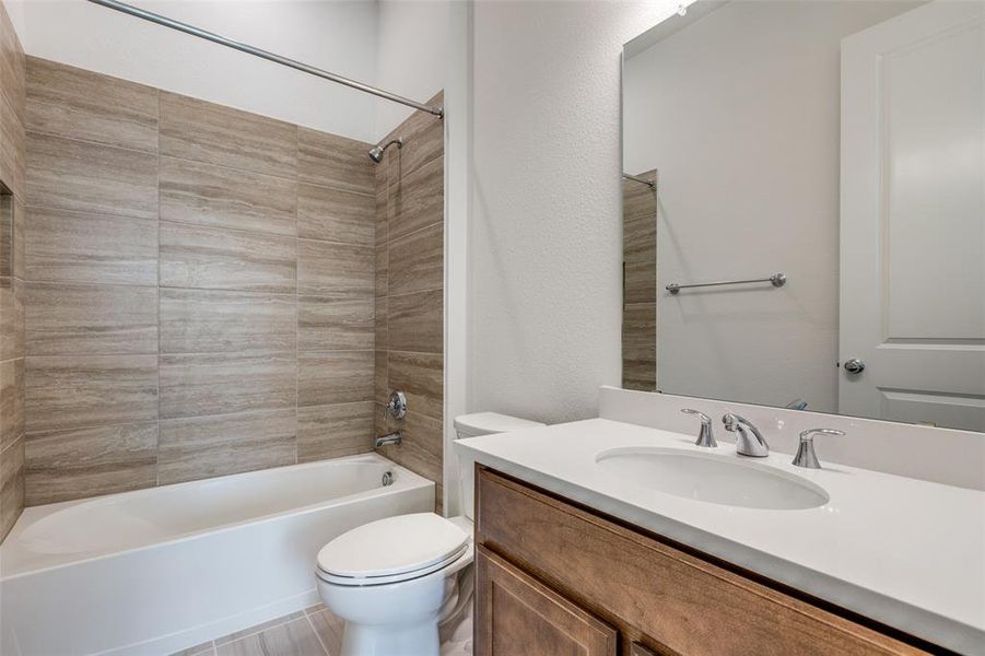 Full bathroom featuring tile floors, tiled shower / bath, vanity with extensive cabinet space, and toilet