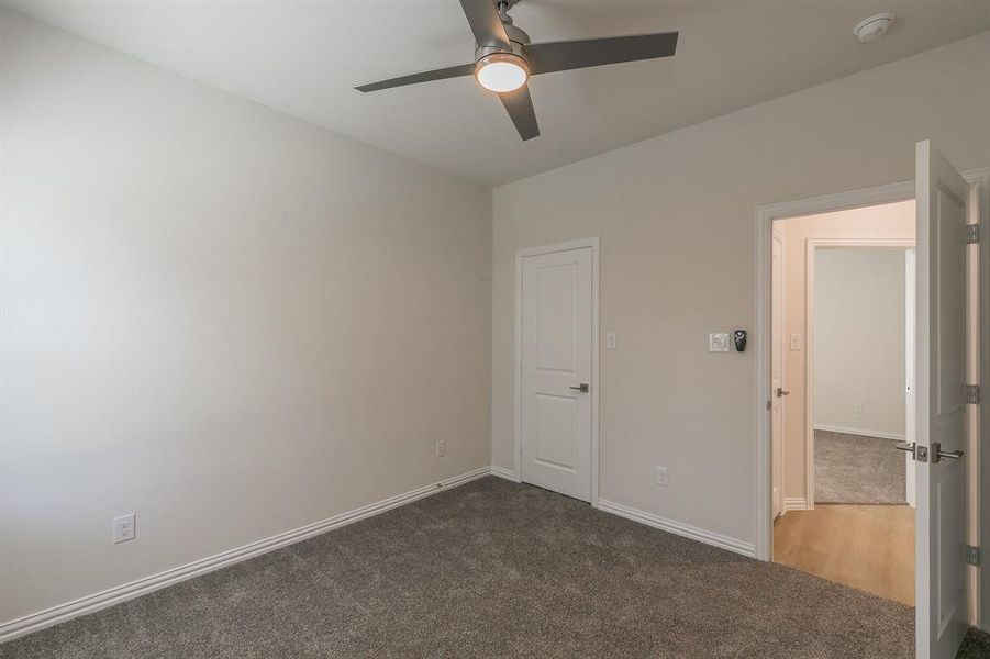 Carpeted spare room featuring ceiling fan