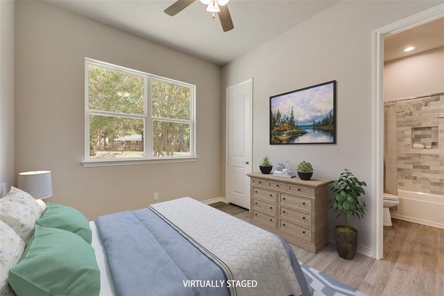 Bedroom with ceiling fan, light wood-type flooring, and ensuite bath