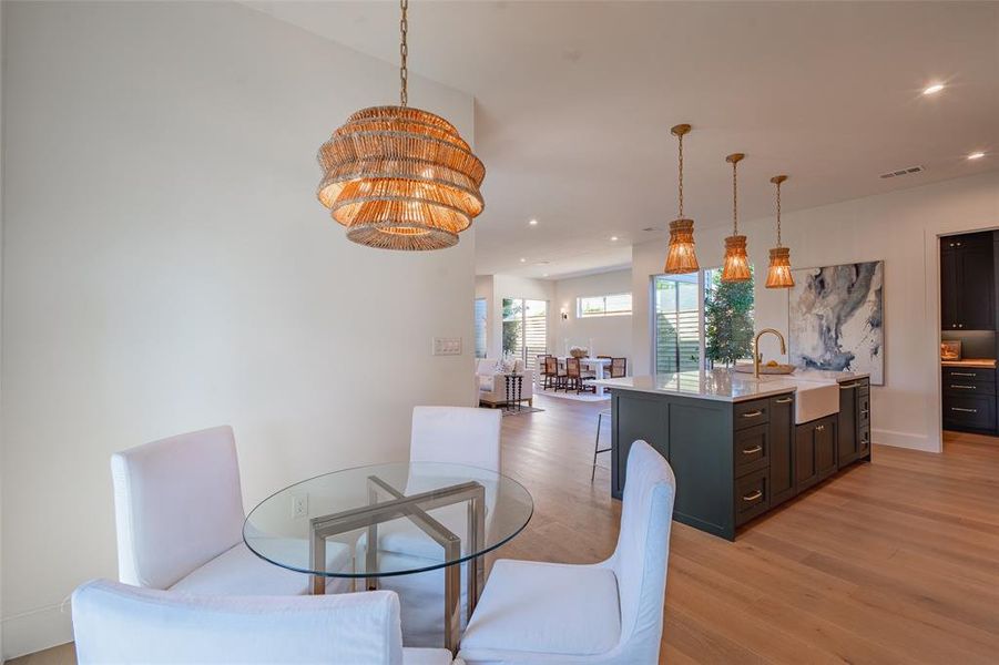 Dining area featuring light hardwood / wood-style flooring, sink, and a notable chandelier