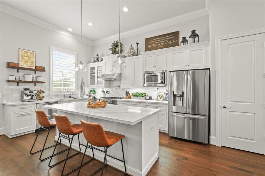 Host your next dinner party with confidence! This masterfully-equipped kitchen features a kitchen island, an abundance of cabinetry and hardware, plantation shutters, under cabinet lighting, quartz countertops, stainless-steel appliances, and a walk-in pantry.