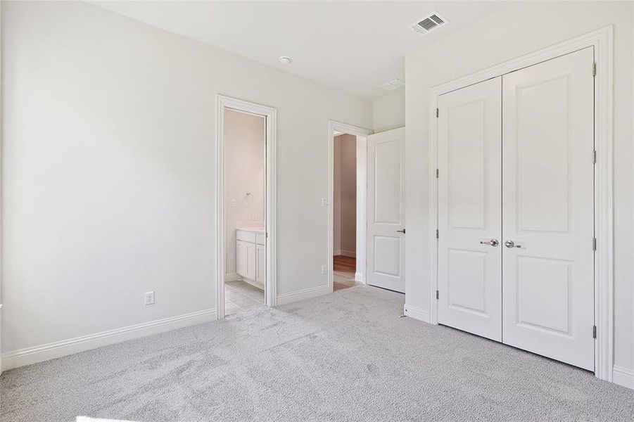 Unfurnished bedroom featuring a closet, connected bathroom, and light carpet