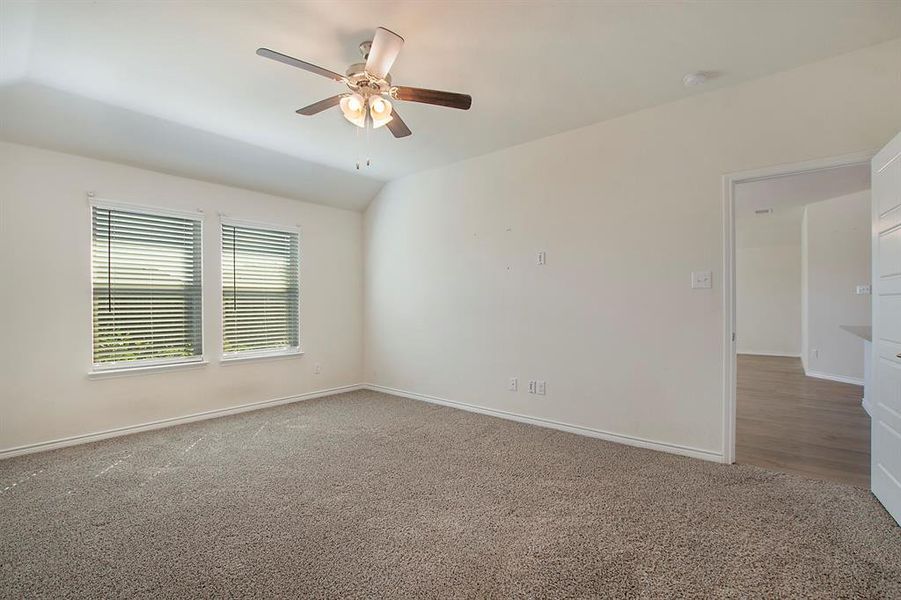 Empty room with ceiling fan, carpet, and lofted ceiling