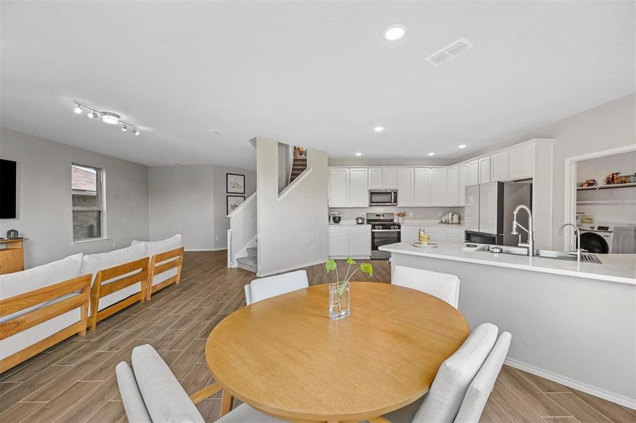 Dining room with washer / clothes dryer, sink, rail lighting, and light wood-type flooring