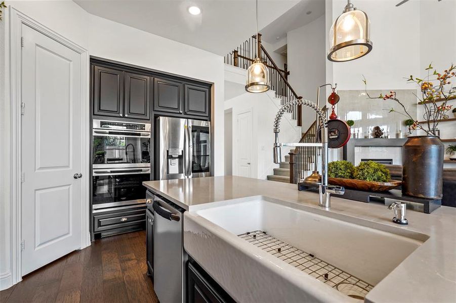 Kitchen featuring dark hardwood / wood-style flooring, appliances with stainless steel finishes, a fireplace, decorative light fixtures, and sink