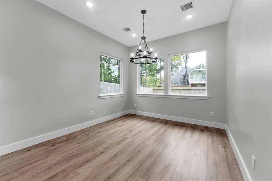 Light filled dining area off kitchen includes iron chandelier and backyard views