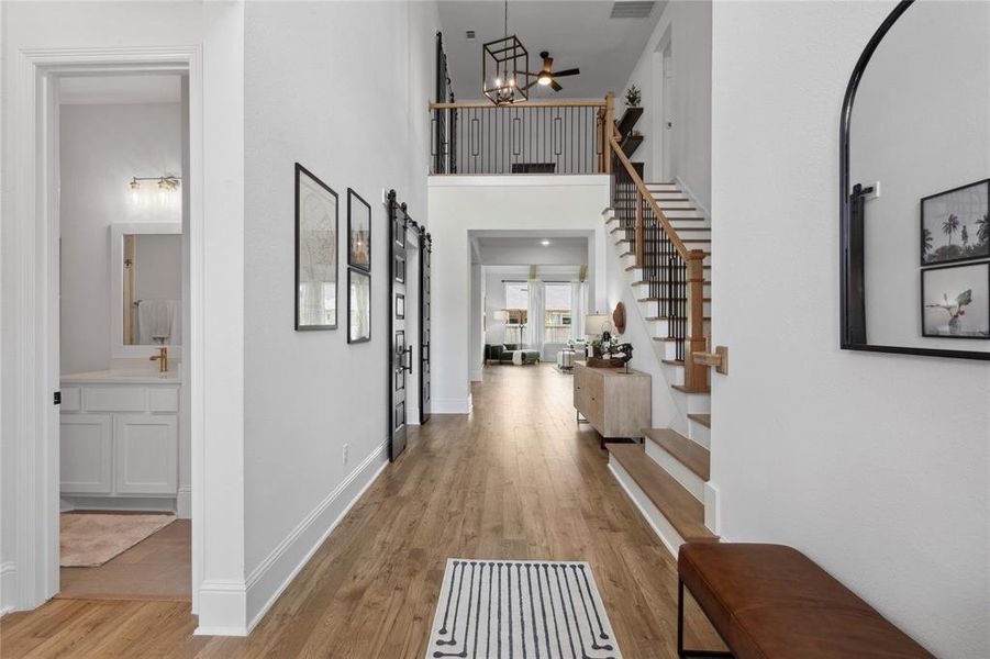 Forged iron front door opens to elegant foyer, with guest bath and bedroom to the left.