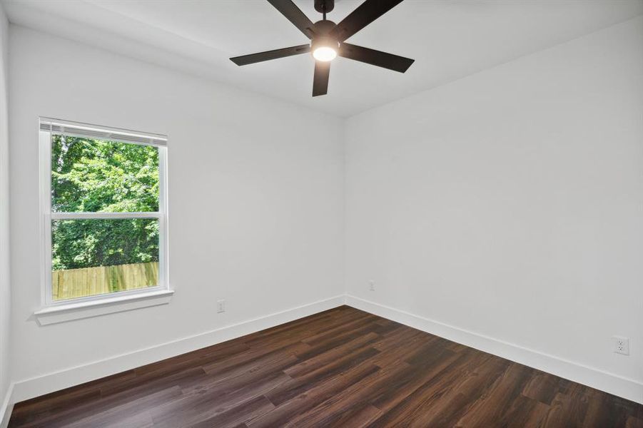 Spare room featuring dark wood-type flooring, plenty of natural light, and ceiling fan