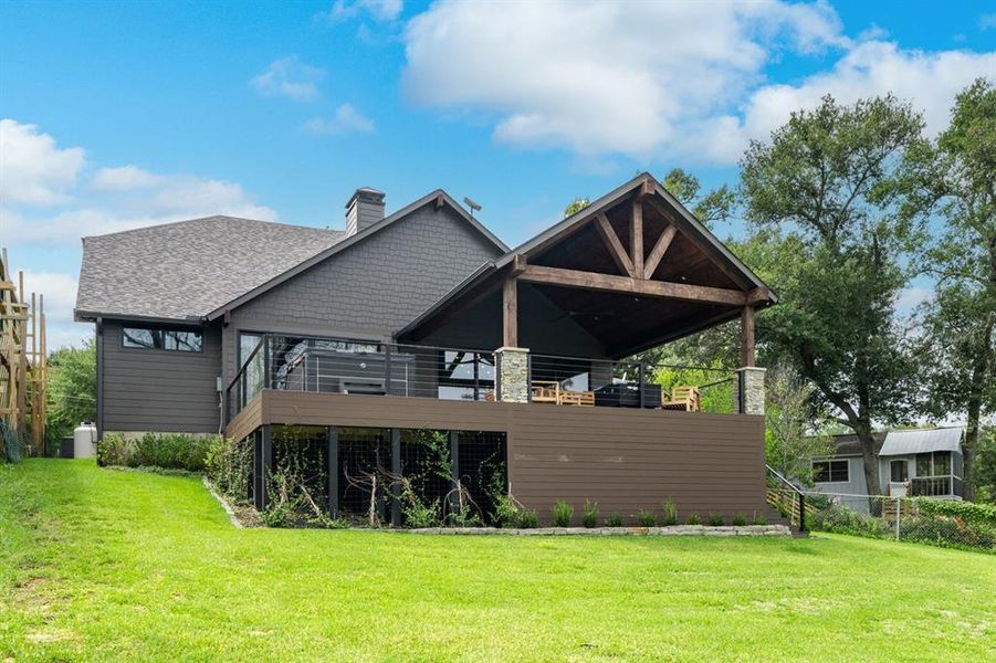 Rear view of house featuring a deck and a lawn