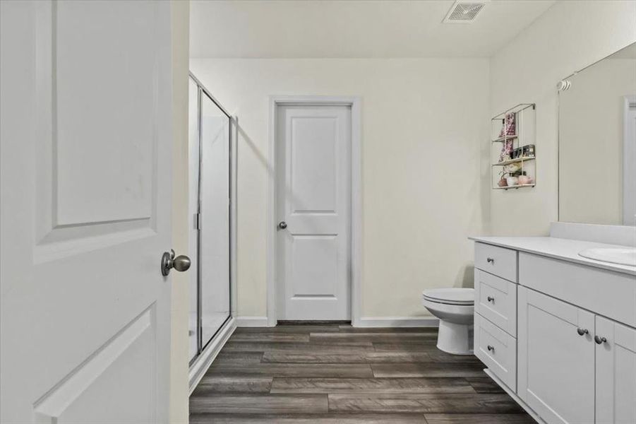 Bathroom with vanity, wood-type flooring, a shower with shower door, and toilet