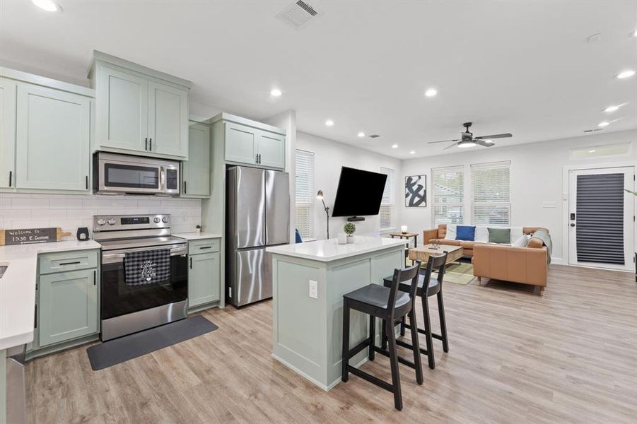 Kitchen with light hardwood / wood-style flooring, stainless steel appliances, and green cabinetry