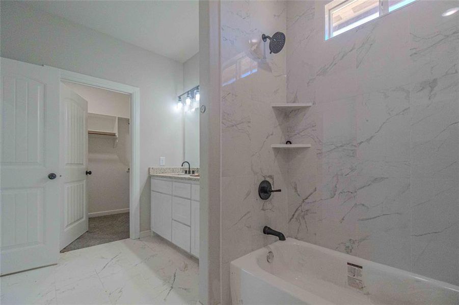 Bathroom featuring tile flooring, plenty of natural light, vanity, and tiled shower / bath combo