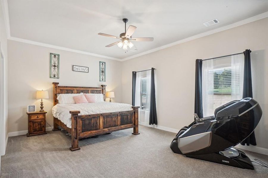 Carpeted bedroom featuring ceiling fan and crown molding