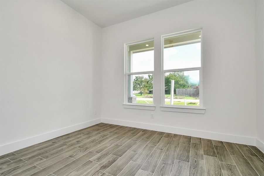 Bedroom 1 features elegant 2-panel doors, a ceiling fan, and two recessed lights for optimal illumination. Enjoy natural light from two forward-facing windows, and ample storage within the closet. The room is finished with stylish wood-like tile flooring.