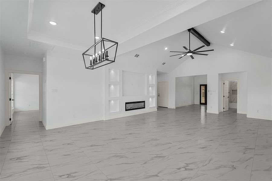 Unfurnished living room featuring ceiling fan with notable chandelier, beam ceiling, and high vaulted ceiling