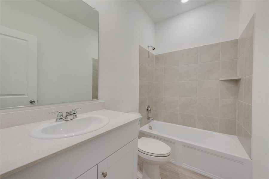 Full bathroom with vanity, toilet, wood-type flooring, and tiled shower / bath