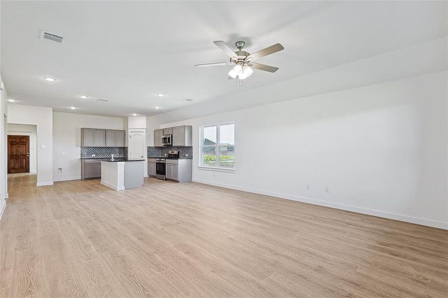 Unfurnished living room featuring ceiling fan and light hardwood / wood-style floors