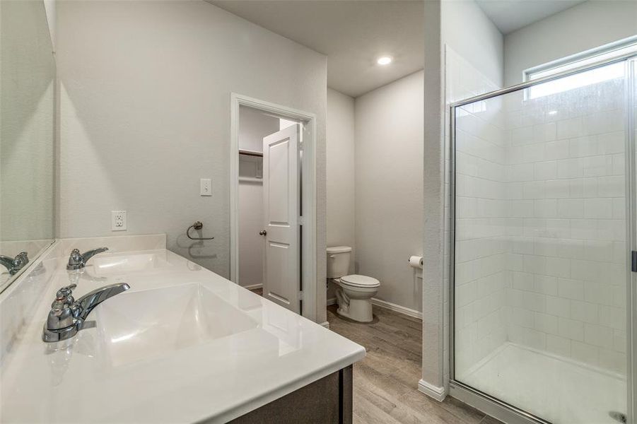 Bathroom with dual vanity, toilet, walk in shower, and hardwood / wood-style floors