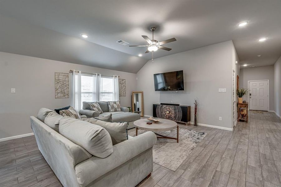 Living room featuring lofted ceiling, light hardwood / wood-style floors, and ceiling fan