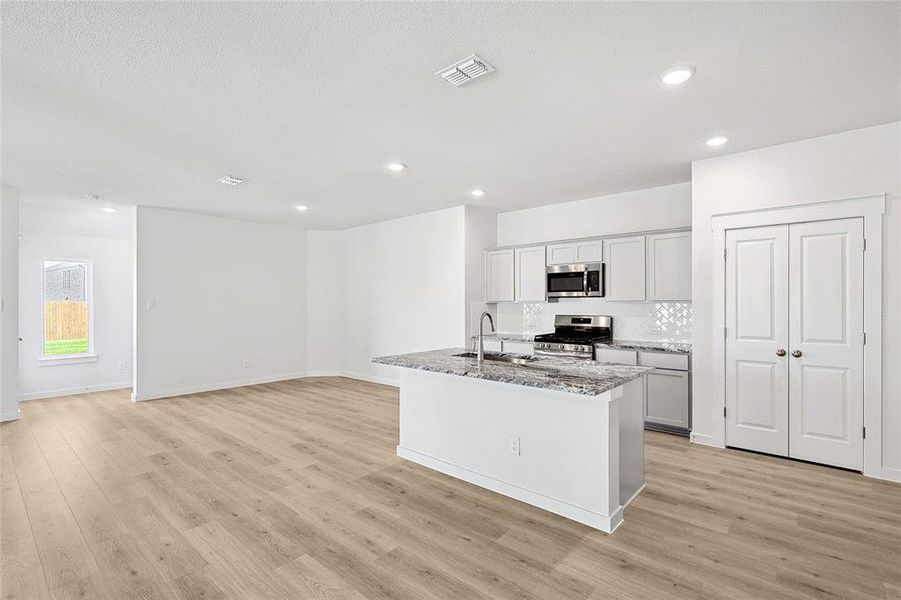 Kitchen featuring backsplash, stainless steel appliances, light hardwood / wood-style floors, sink, and a kitchen island with sink