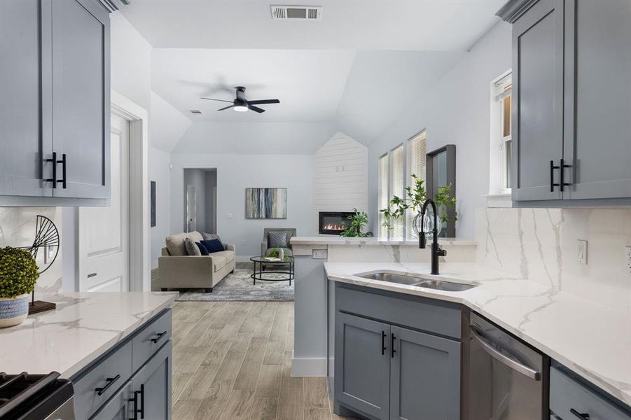 Kitchen with gray cabinetry, lofted ceiling, appliances with stainless steel finishes, and sink