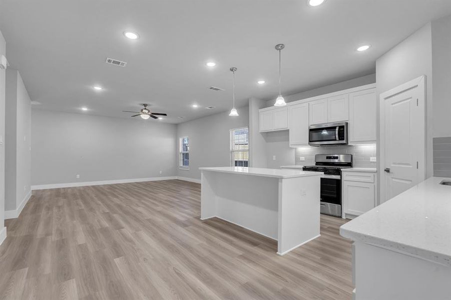 Kitchen with ceiling fan, pendant lighting, stainless steel appliances, and white cabinets