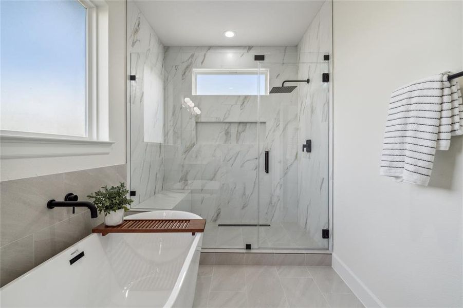 Indulge in a spa-like experience with this stunning walk-in shower, adorned with elegant white tiles, an oversized shampoo niche, and a built-in bench for ultimate comfort