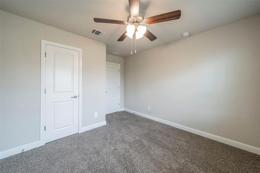 Unfurnished bedroom featuring ceiling fan and carpet