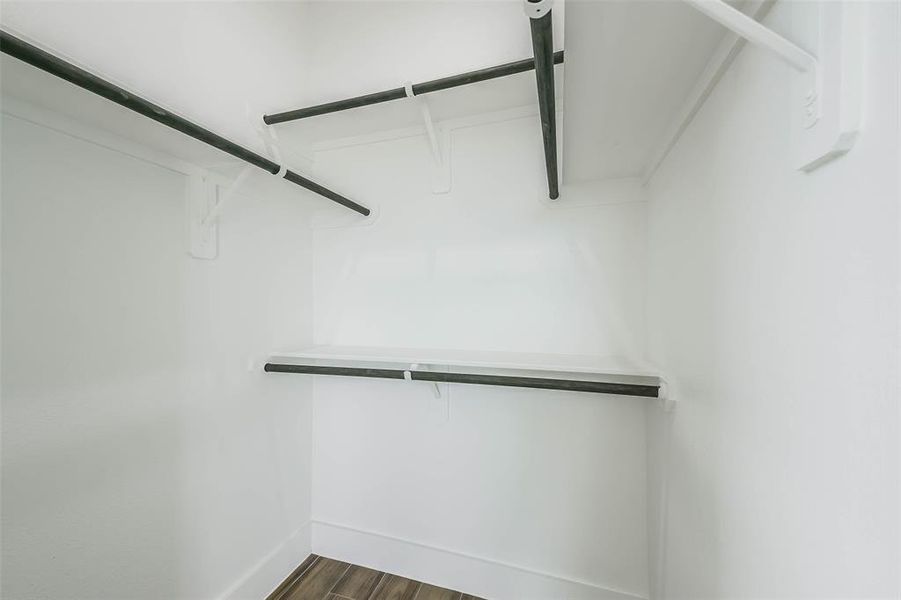 This is a clean, empty walk-in closet with built-in shelves and hanging rods, featuring ample space for storage and organization.